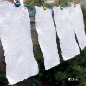 An image of Mnshaa handmade paper hanging outside for drying. it is a part of paper making process. This paper is 100% cotton rag, Rough texture and four deckled edges, mid-rough texture and a heavyweight 250 gsm. Entirely unique in tone and grain. Perfect for use with watercolour, inks and other drawing media.